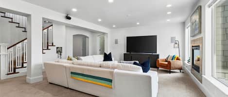 Un salon moderne avec un canapé blanc, un téléviseur à écran plat et une cheminée.