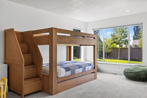 Ein Schlafzimmer mit einem hölzernen Himmelbett, einer eingebauten Treppe und einem großen Fenster mit Blick ins Freie.