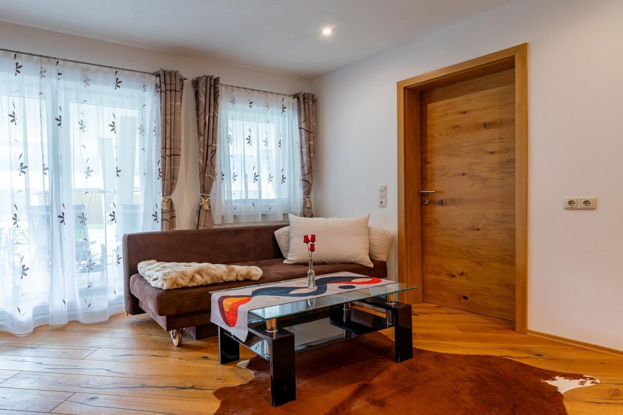 A living room with a sofa, a glass coffee table, and a wooden door.