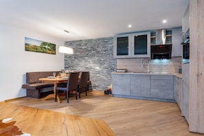 Une cuisine moderne avec des meubles gris, un pare-feu en pierre et un coin repas comprenant une table et des chaises en bois.