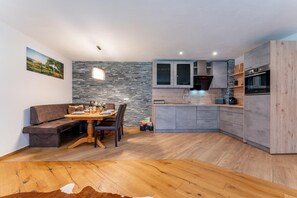 Une cuisine moderne avec des meubles gris, un four encastré et un pare-feu en pierre.
