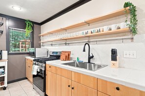 Eine moderne Küche mit Holzausstattung, einer Edelstahlspüle und einem Gasherd.