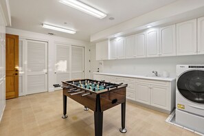 A clean, modern kitchen with white cabinets, a built-in washing machine, and a foosball table. - Private Pool + Spa | Templeton El Pomar District | Krisyn Vineyards (Templeton)