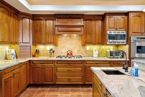 A kitchen with wooden cabinets, a gas stove, a microwave, and a stainless steel oven. - Private Pool + Spa | Templeton El Pomar District | Krisyn Vineyards (Templeton)