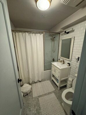 Une salle de bain équipée d’une douche, de toilettes, d’un lavabo et d’un miroir.