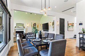 Uma sala de jantar moderna com uma mesa comprida, várias cadeiras e um lustre.