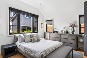 A bedroom with a large bed, a dresser, and a window with a view of greenery. - Pool + Hot Tub + Firepit + BBQ | Walk to Melrose + The Grove | Crescent Peak (West Hollywood)