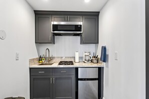 A compact kitchen with a microwave, stove, and dishwasher. - Pool + Hot Tub + Firepit + BBQ | Walk to Melrose + The Grove | Crescent Peak (West Hollywood)