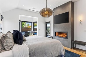 Un dormitorio moderno con una cama grande, una chimenea y vistas al exterior.