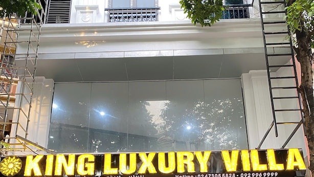 Entrada de un hotel con un letrero que dice 'KING LUXURY VILLA' y una escalera que conduce a la entrada.