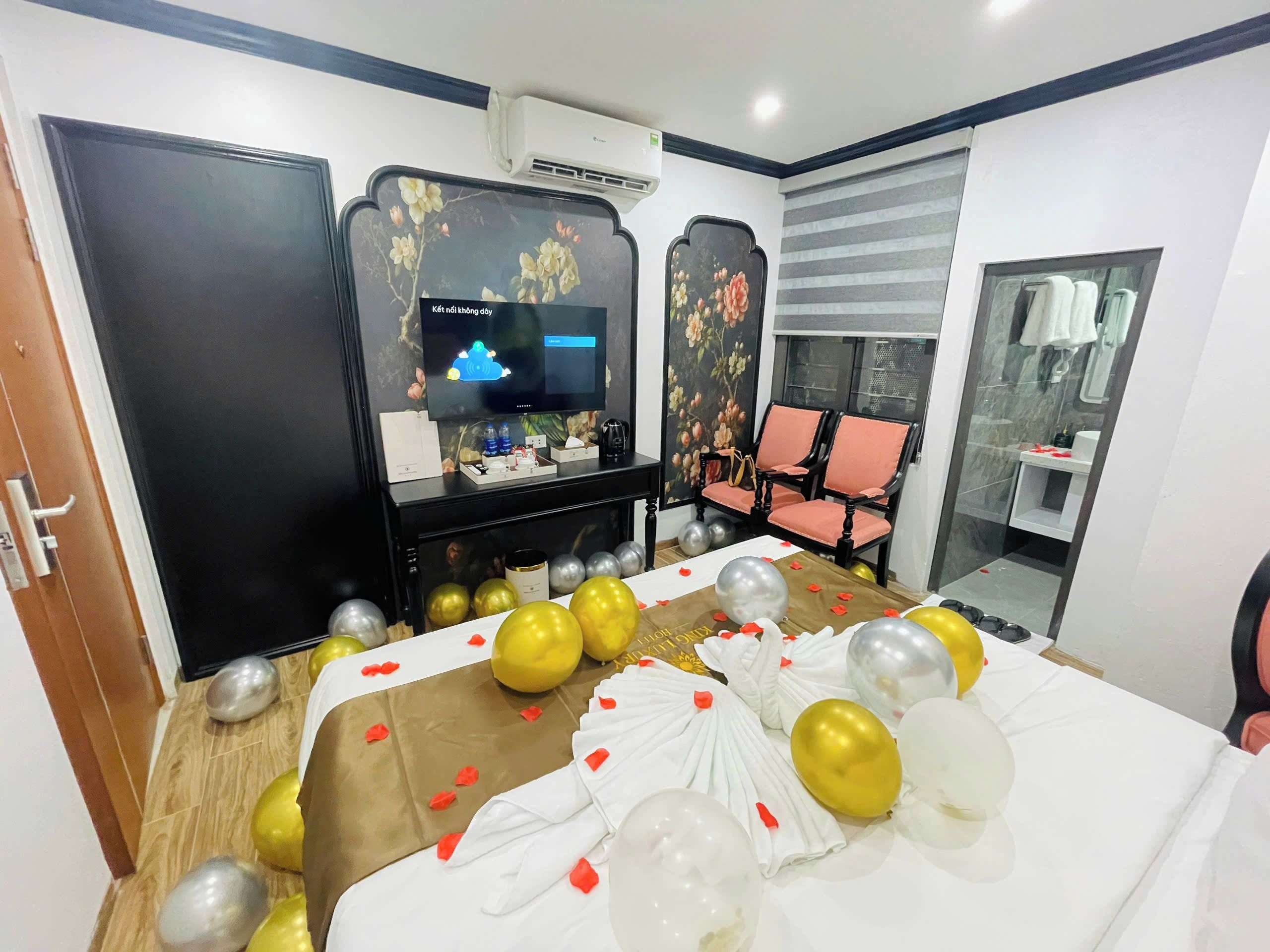 Una habitación de hotel con cama, televisión, espejo y zona de estar.