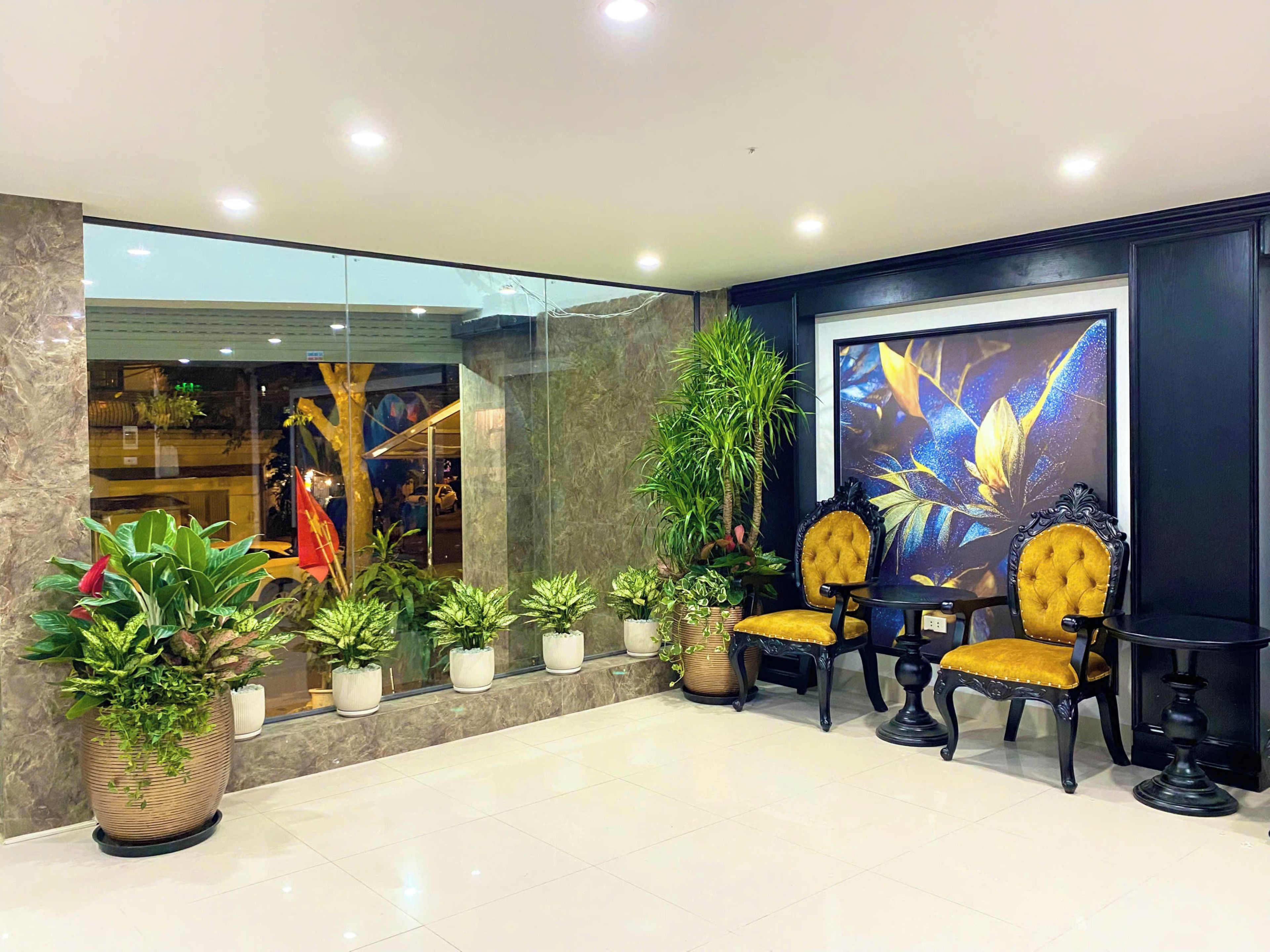 A lobby with a seating area, potted plants, and a large window.