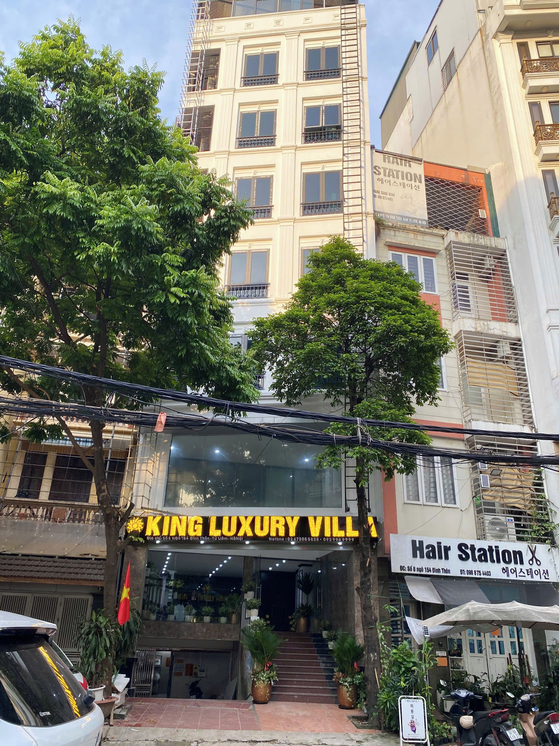 A building with a sign for 'King Luxury Villa' and a 'Hair Station' across the street.