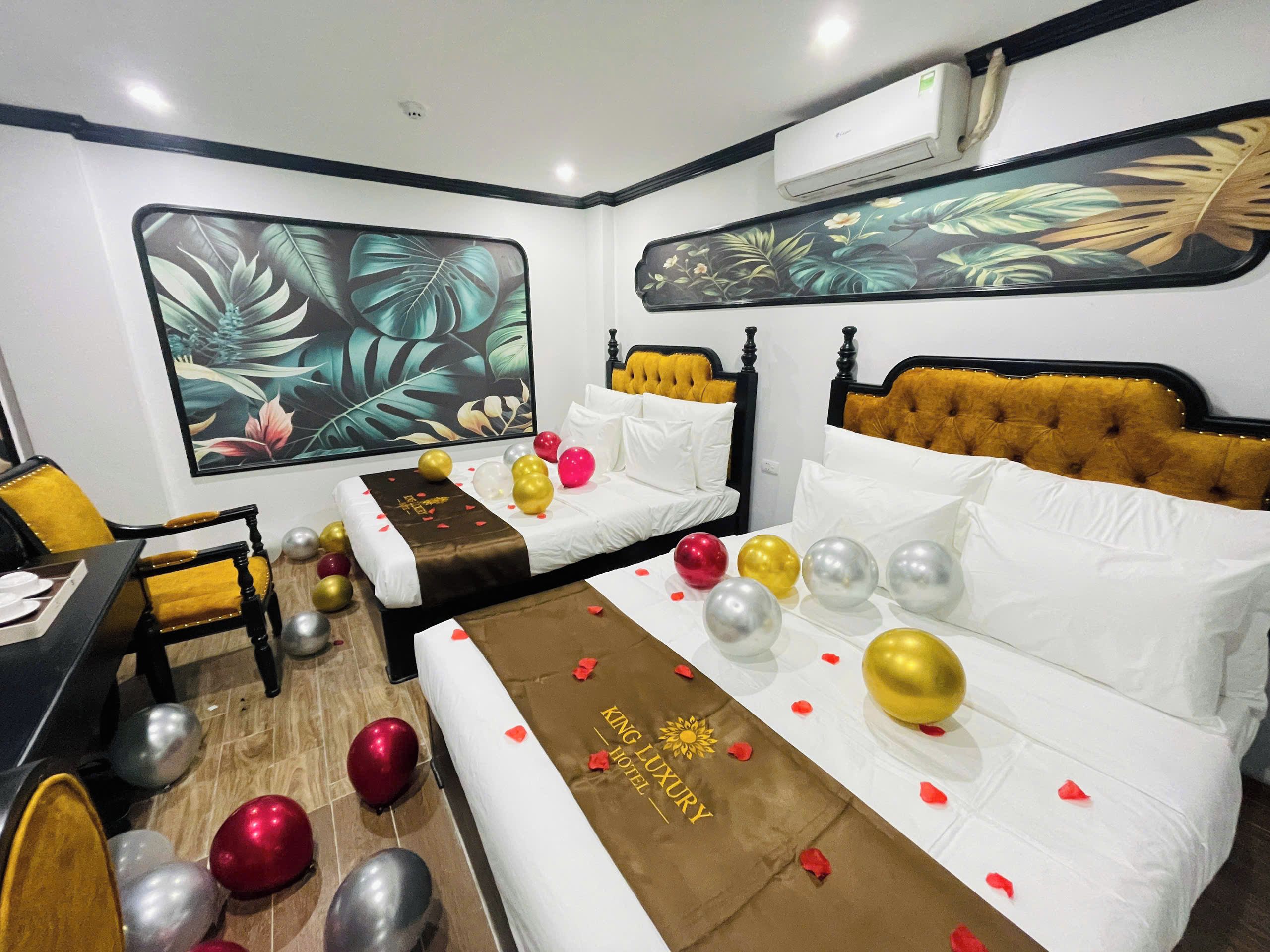 A hotel room with two beds, a large tropical leaf mural, and a minibar.
