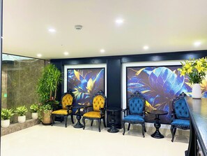 A reception area with a seating arrangement, a large screen displaying floral artwork, and a potted plant. - King Luxury Hotel (Tu Liem)
