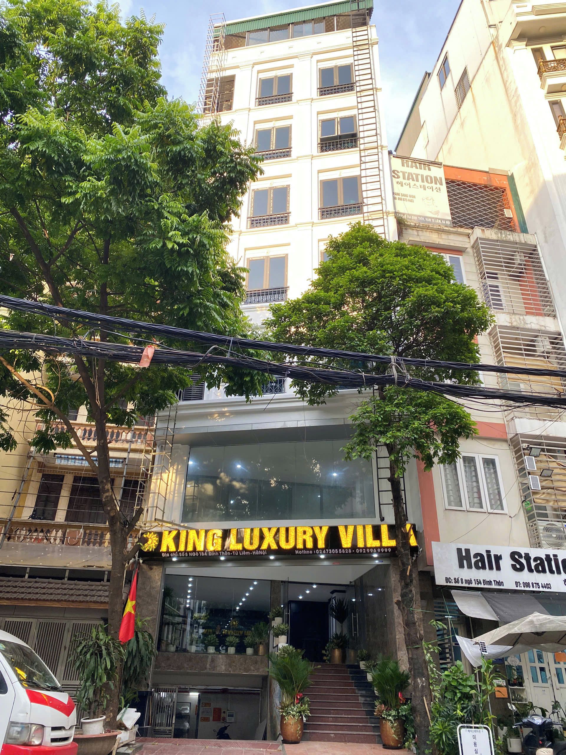 A building with a sign for 'KING LUXURY VILL' and a 'Hair Station' across the street.