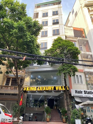 Un edificio con un letrero que dice 'KING LUXURY VILL' y una peluquería al otro lado de la calle.