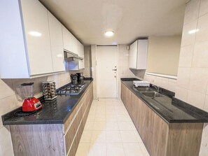A modern kitchen with wooden cabinets, a black countertop, a red blender, and a coffee maker. - Big, Bright & Central Polanco 5BR, Sleeps 17! (Mexico City)
