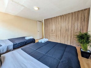A hotel room with two beds, a wooden wardrobe, and a potted plant. - Big, Bright & Central Polanco 5BR, Sleeps 17! (Mexico City)