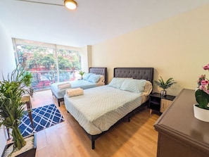 A bedroom with two beds, a balcony, and a view of trees. - Big, Bright & Central Polanco 5BR, Sleeps 17! (Mexico City)