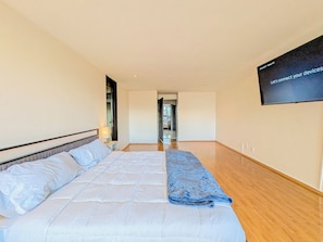Ein Schlafzimmer mit einem Bett, einem an der Wand befestigten Fernseher und Holzdielen.