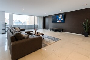 Ein modernes Wohnzimmer mit einer Eckcouch, einem Couchtisch und einem an der Wand montierten Flachbildfernseher.