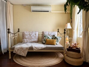Une chambre avec un lit, un climatiseur, une lampe et une plante.