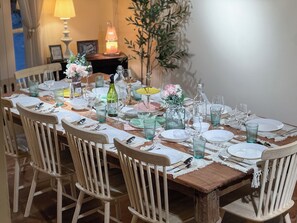 A dining table set with plates, glasses, and cutlery, surrounded by wooden chairs. - 4-bedroom Spanish Hacienda 10 mins MRT Huaykwang/JODD Fair/RCA (Krung Thep Maha Nakhon)