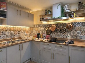 A kitchen with a tiled backsplash, stainless steel appliances, and a variety of cookware. - 4-bedroom Spanish Hacienda 10 mins MRT Huaykwang/JODD Fair/RCA (Krung Thep Maha Nakhon)