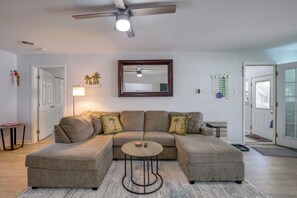 A living room with a sectional sofa, a round coffee table, a ceiling fan, and a large mirror on the wall. - 1 Mi to Beach! Family-Friendly Waveland Home (Waveland)