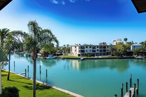 A marina with boats docked, a building with multiple balconies, and a clear blue sky. - Pet-Friendly Condo Near the Beach w/ Boat Slip (Treasure Island)