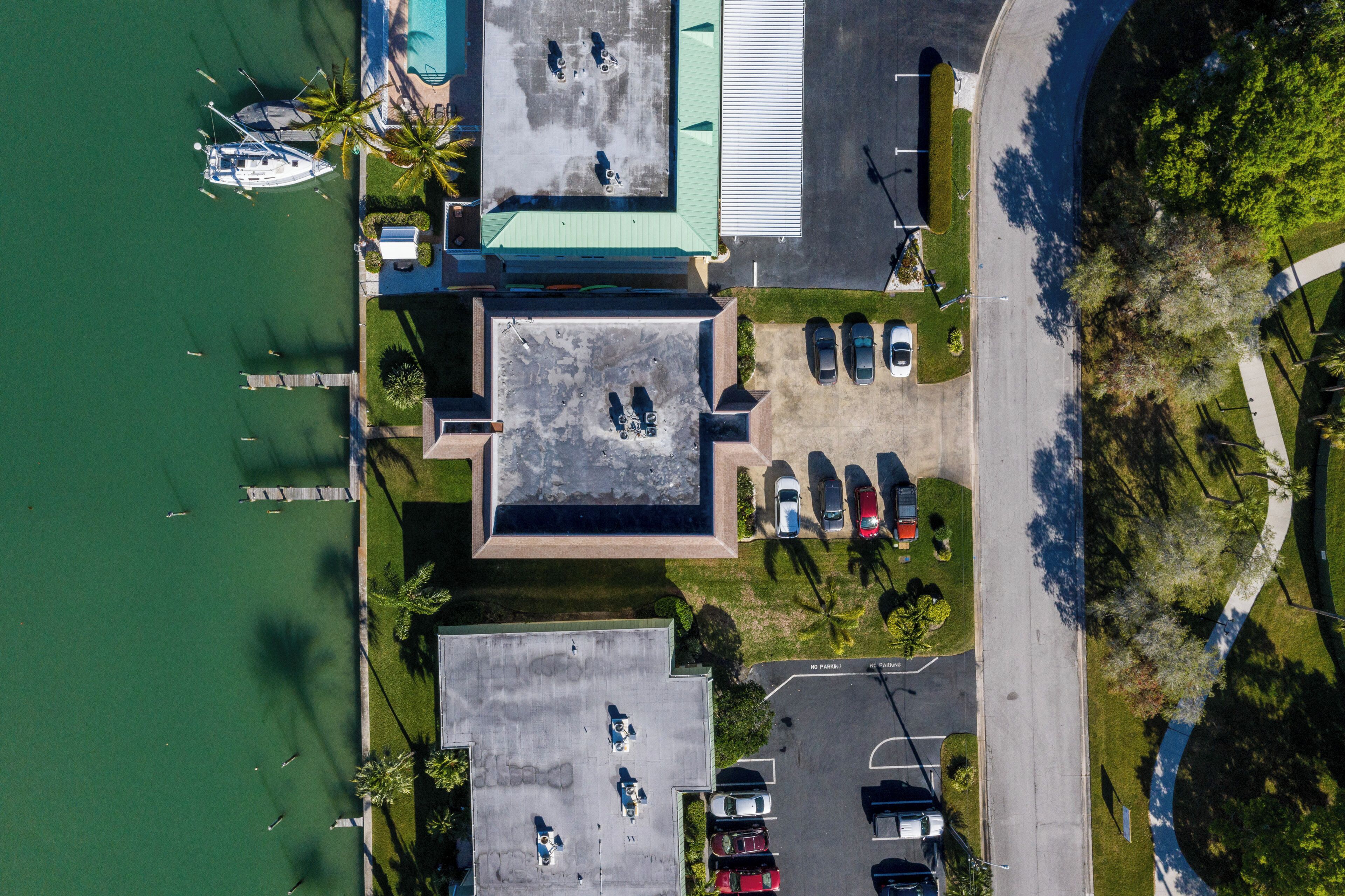 An aerial view of a property with a marina, parking area, and buildings with flat roofs.