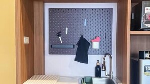 Uma cozinha compacta com painel perfurado, pia e geladeira.