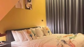 Quarto com cama, cortinas e uma cadeira vermelha.