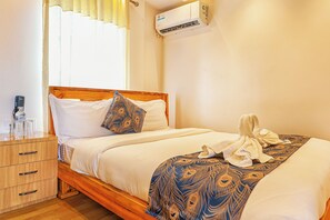 A hotel room with a wooden bed, a bedside table with a bottle and glasses, and a window with curtains. - Thumki Resort (Panaoti)