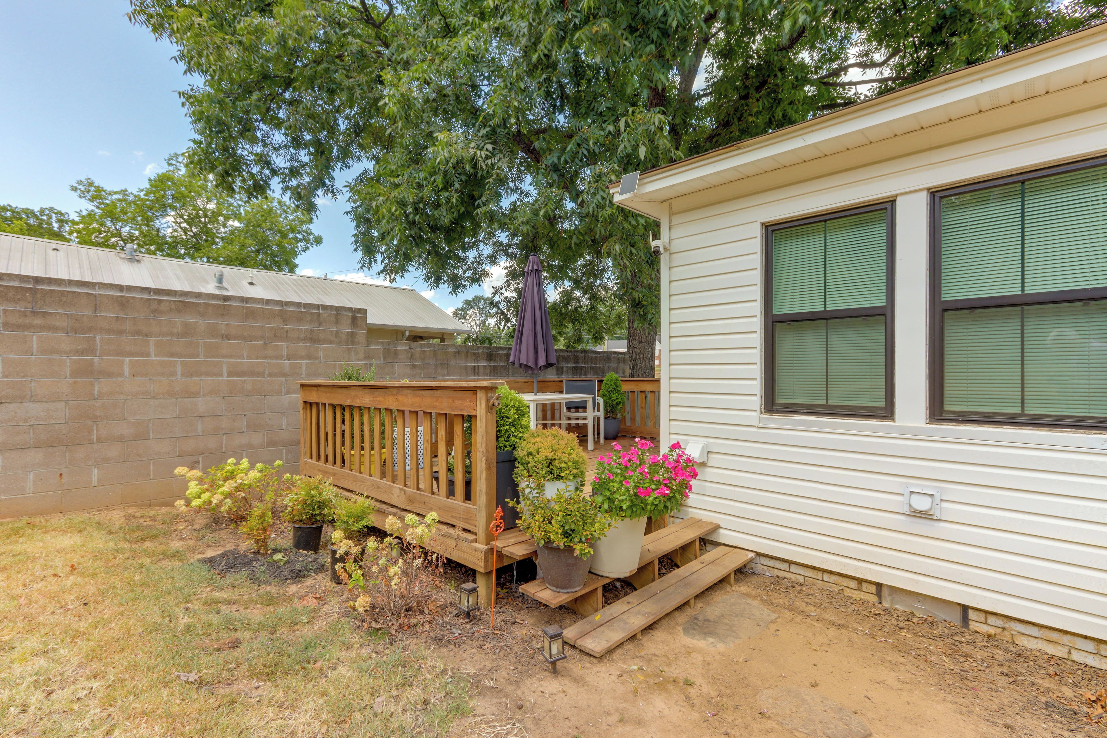 A single-story house with a wooden deck, potted plants, and a small patio area.