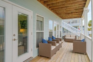 Eine überdachte Veranda mit Korbmöbeln und einer Holztreppe.