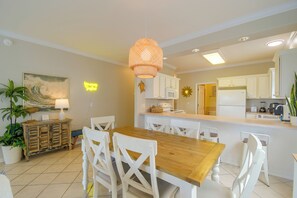Een moderne keuken met witte kasten, een houten eettafel en een hangende hanglamp.
