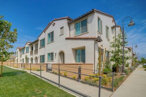 A multi-story residential building with a consistent architectural style, featuring a flat roof, white exterior walls, and green shutters on the windows. - Townhome w/ Several New Haven Community Perks! (Ontario)