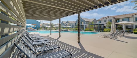 A covered outdoor area with lounge chairs and a swimming pool.