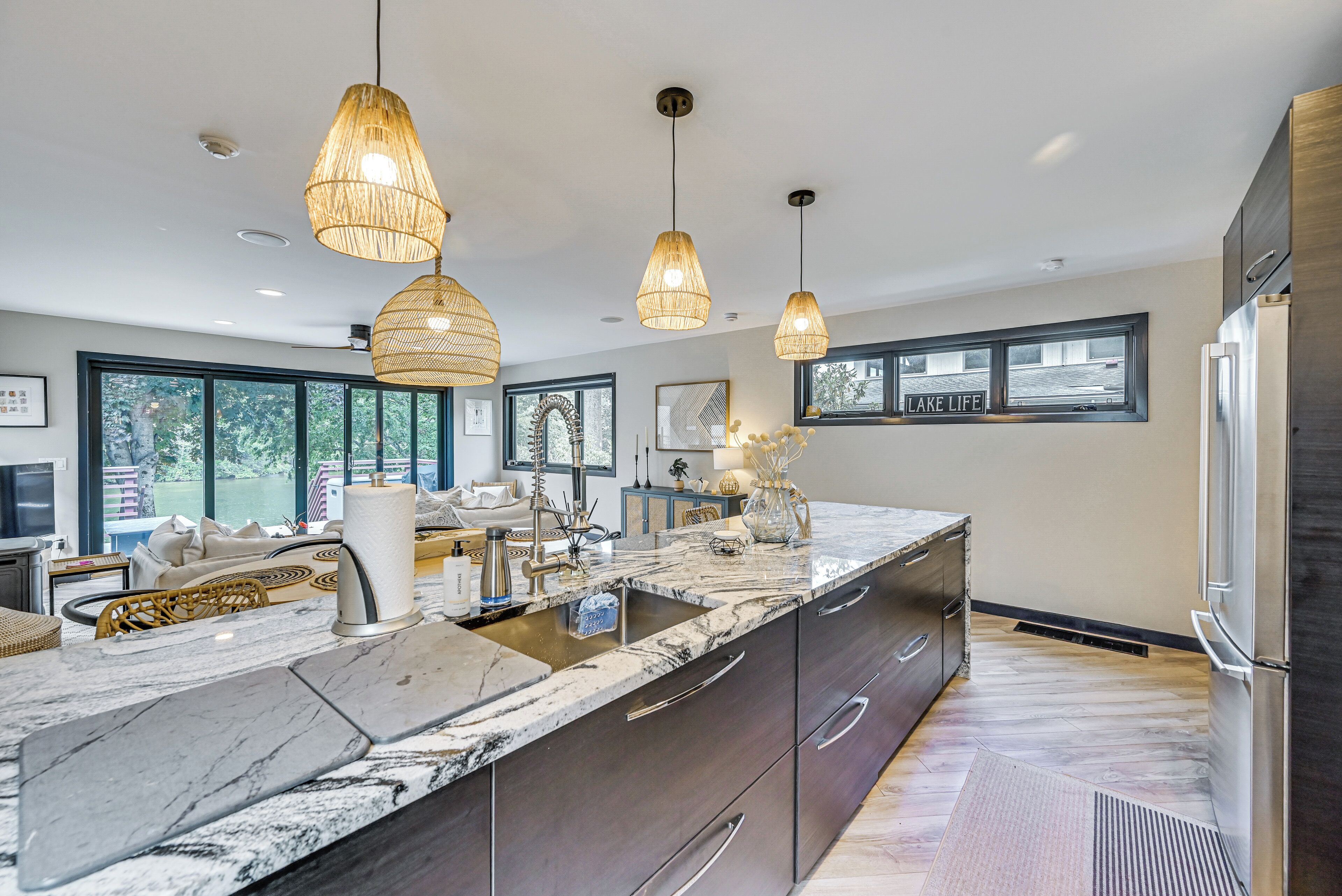 Een moderne keuken met een marmeren aanrechtblad, roestvrijstalen apparatuur en hangende lampen.