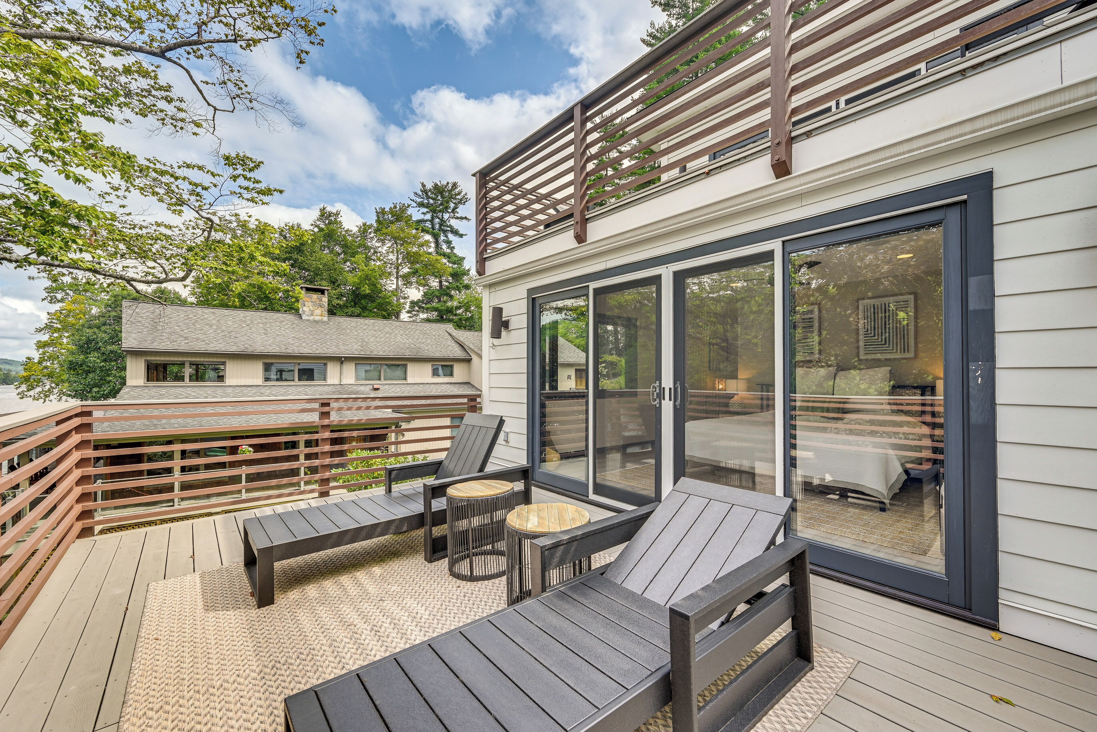A deck with outdoor furniture, a pergola, and a glass door leading to an interior space.