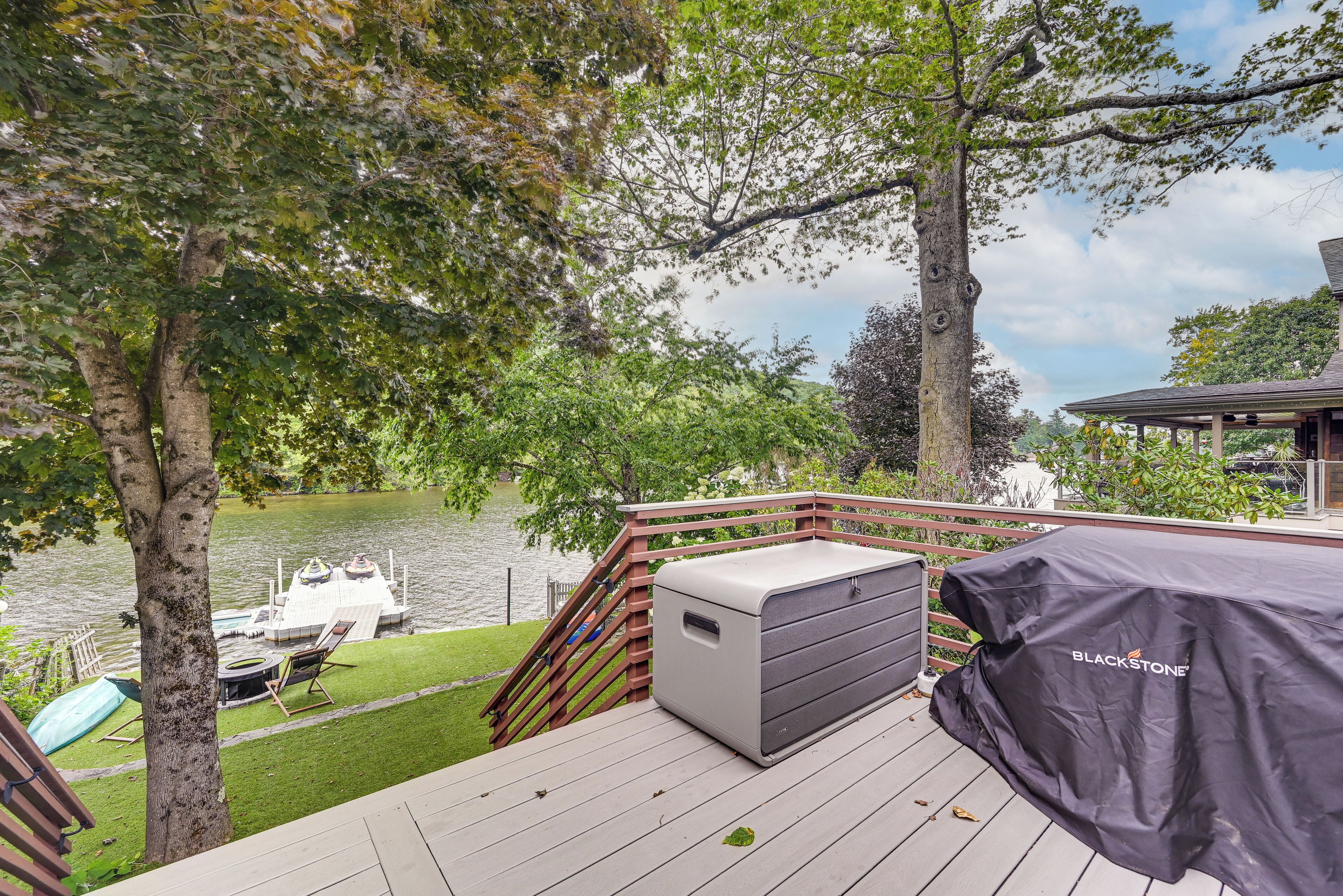 A deck with a grill, a boat, and a view of a lake.