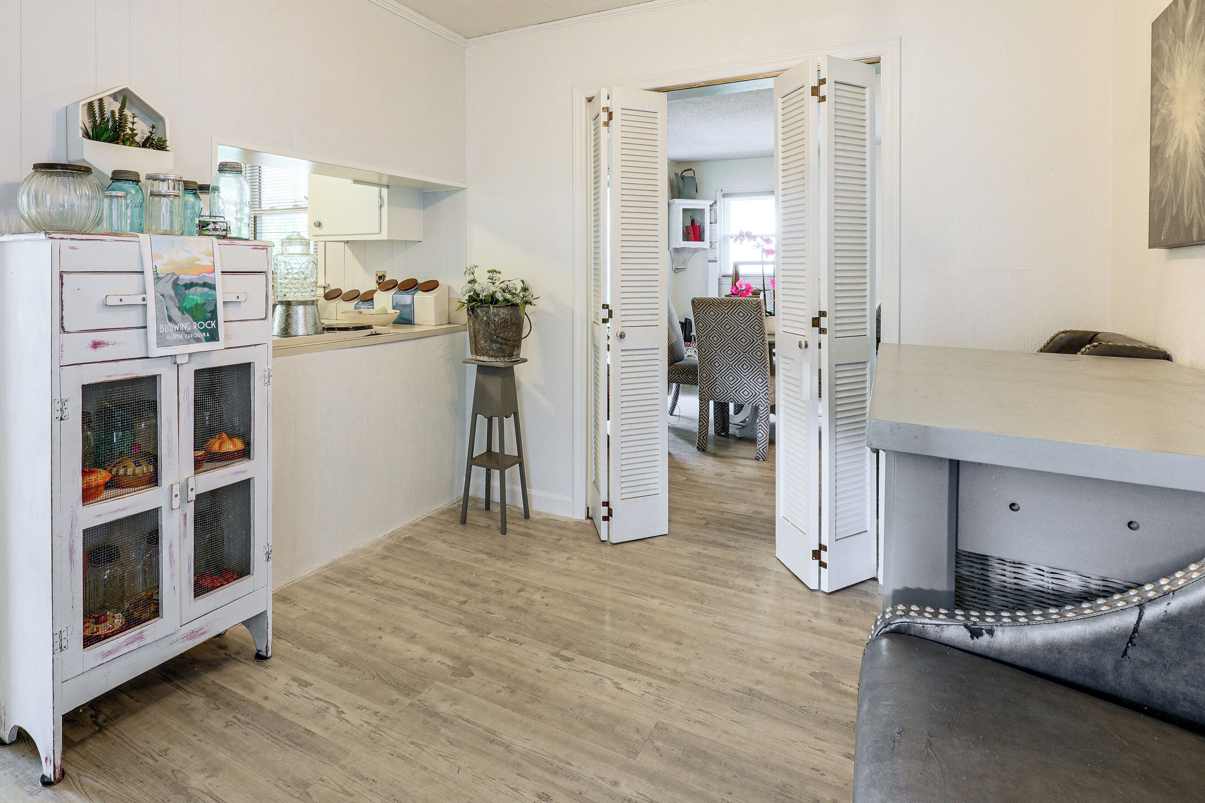 A room with a kitchenette, a dining area with a table and chairs, and a door leading to another room.