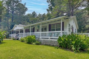 A two-story house with a covered porch, surrounded by a well-maintained lawn and dense trees. - Wraparound Porch! Quiet Country Home, 9 Mi to MSU (Starkville)
