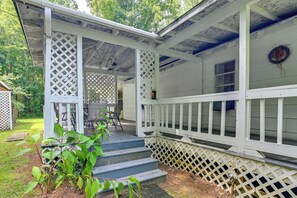 A covered porch with a wooden railing, a table with chairs, and a small garden area with plants. - Wraparound Porch! Quiet Country Home, 9 Mi to MSU (Starkville)