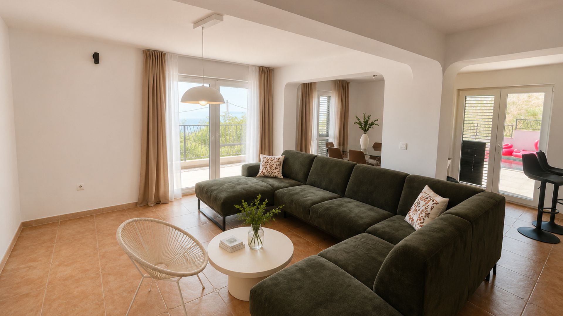 Ein modernes Wohnzimmer mit einem Ecksofa, einem runden Couchtisch und einem Korbstuhl.