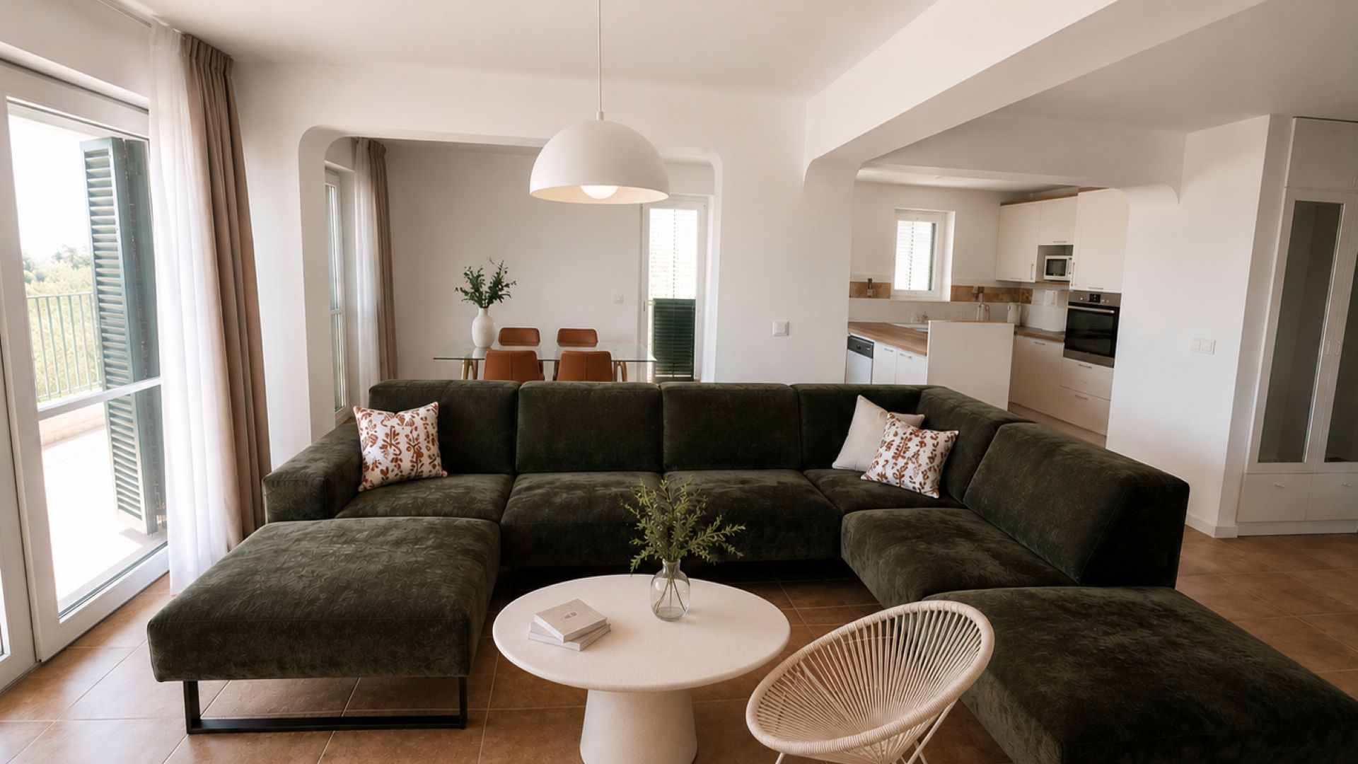 Een moderne woonkamer met een hoekbank, een ronde salontafel en een rieten stoel.