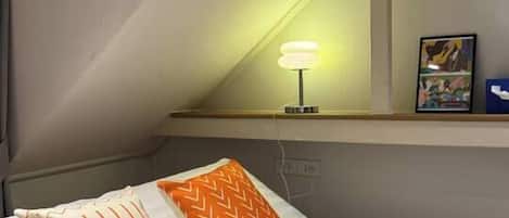 Une chambre d’hôtel avec un lit, une lampe de chevet, un tableau encadré au mur et une fenêtre.