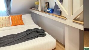 A hotel room with a bed, a window with curtains, a shelf with items, and a staircase. - Nueng Rana 113 Unique House in Chinatown 3BR 2BA - Villa (Khet Samphanthawong)